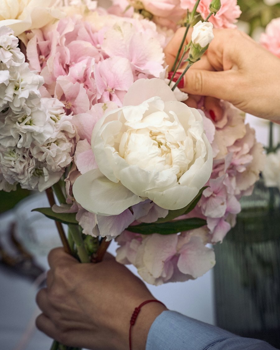 Hands arranging a bouquet of peonies and hydrangea